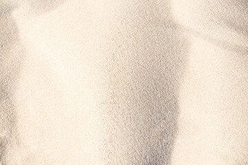 Sunny sand of a dune. Sand texture. Sandy beach for the background. Top view. Background, sand, light, beige, wave, reflect, shadow, summer.