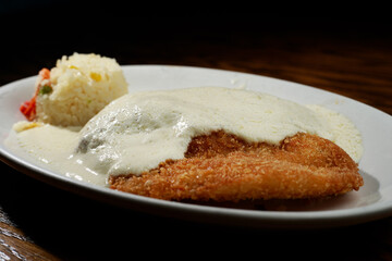 plato arreglado de filete de pescado capeado a los tres quesos