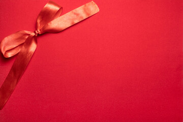 Red ribbon bow on red background. Red background made from paper.