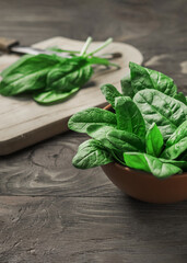 Fresh spinach leaves in a bowl on a rustic wooden table. Selective focus.