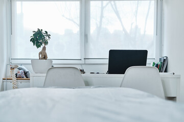 Physiotherapy desktop with a black laptop and a bonsai with an unfocused stretcher