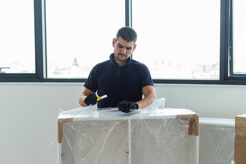 The carpenter unpacking the shelves in the empty living room of the apartment.