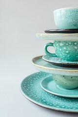 Vertical composition from a handmade turquoise plate and mug on gray background.