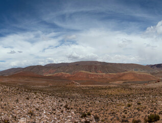 The arid desert. Volcanic landscape. Panorama view of the dry land, valley and mountains under a beautiful sky high in the Andes mountain range.