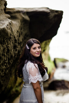 Newlywed Bride Standing Between Rocks on Beach in San Diego