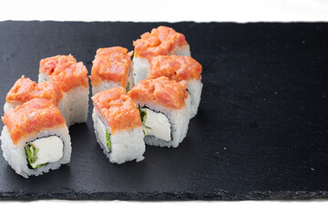 Traditional delicious fresh sushi roll on a black background with reflection. Sushi roll with rice, cream cheese, red fish, salmon. Japanese cuisine, restaurant. Seafood, Asian cuisine. Hot sushi