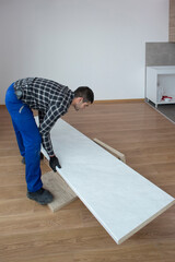 The carpenter unpacking the shelves in the empty living room of the apartment.