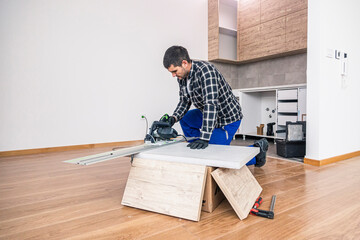 A carpenter cutting a wooden board on the floor of the room