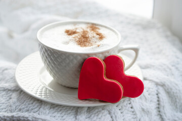 Valentine's day card. Breakfast. White cup  of hot coffee with milk and  red cookies  shaped  heart on white background.