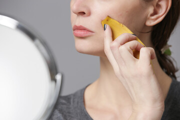 Woman rubbing banana peel on her face to brighten and hydrate skin and reduce wrinkles. Zero waste...