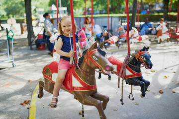 Toddler having fun on vintage French merry-go-round in Paris