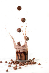 chocolate candies falling into a cup of chocolate milk
