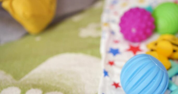 A young mother sits on the bed with a small child in her arms and controls the game with a teether and other tactile toys. Maternity, motherhood and family concept
