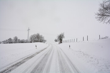 Fototapeta na wymiar Snow-covered lonely country road in winter in the countryside