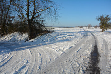 Fototapeta na wymiar Snowy road in winter in the countryside with tire tracks