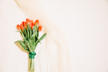 bouquet of tulips. Bouquet of red tulips on a white background with beige tulle. Wedding card with flowers. Copy paste. Spring card with blank space for text 