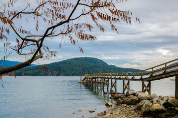 Fototapeta na wymiar Pier in the bay of Deep Cove, sea and mountains, the harbor against the backdrop of a mountain ridge and a cloudy sky