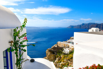 View from a whitewashed terrace with flowers in the village of Oia looking at the sea, caldera and...