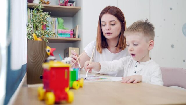 Happy family. Mom and pretty cute son are drawing at leisure at home sitting a table. Mother and preschool child spend time together. Motherhood. hobby and favorite pastime of parents in the nursery