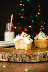 Vanilla cupcake with buttercream icing and christmas colored sprinkles on a wooden table