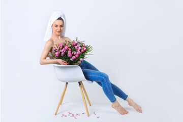 Woman after shower or bath with towel on her head. Beautiful young woman with pink roses. Concept of femininity and tenderness. Advertising. Birthday. spa, skin care. Valentines Day, Mother day