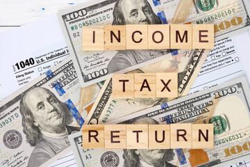 Words income tax return, form 1040 and dollar bills. Tax payment and filing concept. 