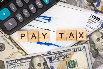 Words pay tax on form 1040, dollar bills and calculator. Tax payment and filing concept. Top view, flat lay