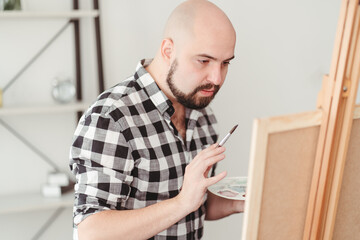 Naklejka na ściany i meble Young painter doing easel drawing at art studio