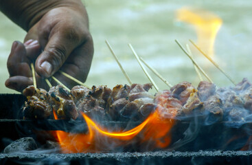 Grilled goat satay over coals, in shallow focus