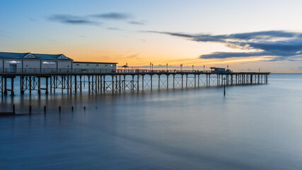 Fototapeta na wymiar Sunrise in long time exposure of Grand Pier in Teignmouth in Devon in England, Europe