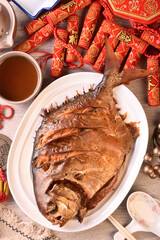 Smoked golden pomfret on white plate. (the Chinese words is 'make money, lucky', not a logo or trademark.)   