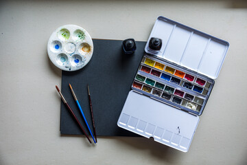 Black notebook with colorful watercolor supplies
