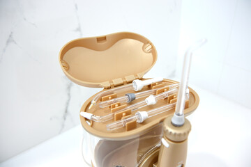 Golden dentist sprinkler irrigator stands on a table with an open lid top view, inside are various nozzles