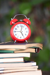 A stack of books and an alarm clock on it