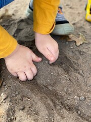 child playing with dirt and cars and trucks with dirty hands 