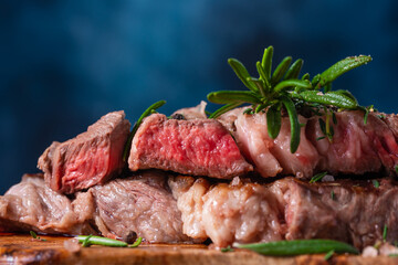 Rare steak with rosemary and seasoning and on a blue background. Fried meat. Tasty food. Recipe book and cooking. Orstration for culinary recipes