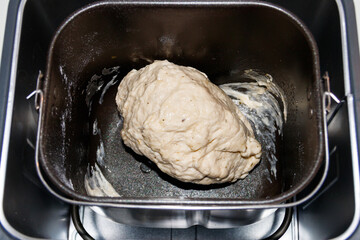 Raw dough in bread pan of electric bread maker