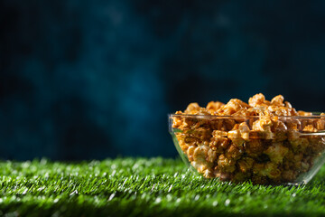 Caramel popcorn in a transparent plate on a blue background Banner with space for an inscription. Relaxation and watching movies. Selling popcorn