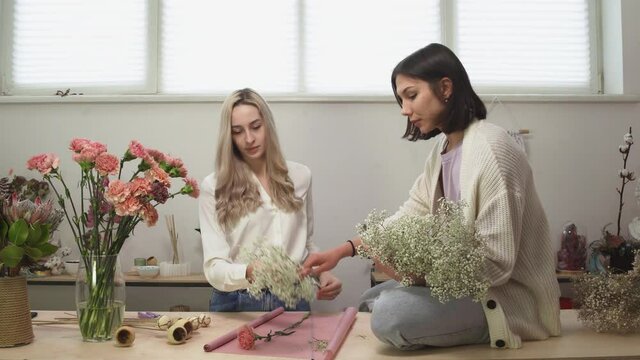 Two female florists in flower shop. Women making a beautiful and stylish bouquet of fresh flowers in floral design studio.