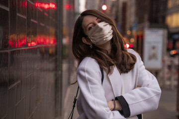Stylish young woman wearing glamorous silk face mask, fashion accessories. Outdoors. Blogging, quarantine protection concept