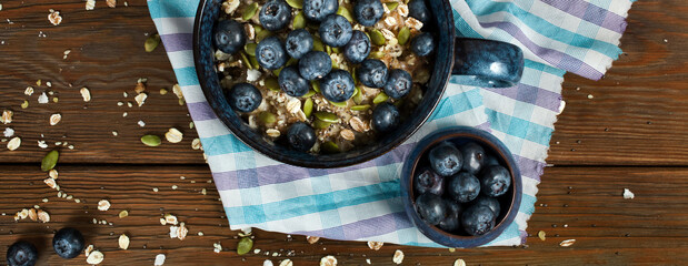 Oatmeal porridge with blueberries and seeds in a blue ceramic bowl on a wooden background. Healthy eating concept. Top view.