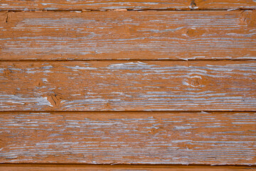 Abstract Rustic aged closeup of barn wood panel painted with orange chipped and faded color. Multiple horizontal slats with wood lines with major knot and texture