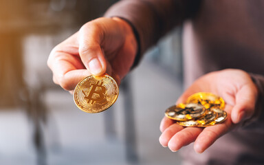 Closeup image of a woman holding and giving gold color bitcoins