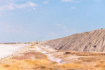 People gathering salt of pink salty Siwash Lake, colored by microalgae, famous for antioxidant properties, enriching water by beta-carotene at sunset