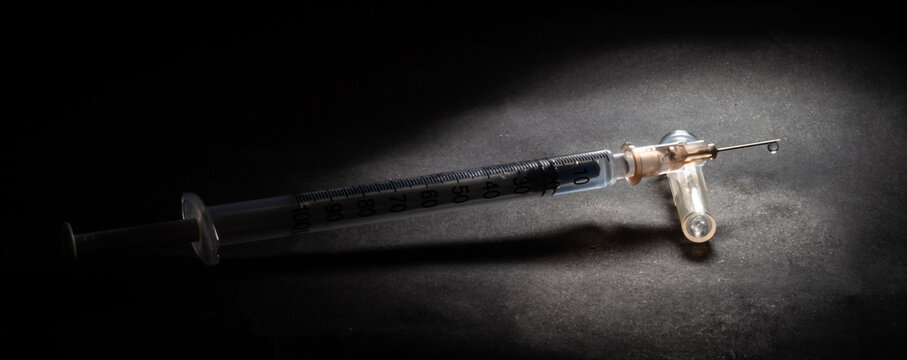 Vacina contra o Covid-19. Conceito dram&aacute;tico com Seringa para vacina&ccedil;&atilde;o em fundo escuro.	