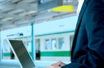 駅のホームでパソコンをするビジネスマン
