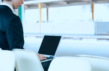 駅のホームでパソコンをするビジネスマン