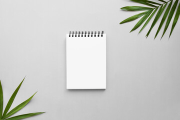 Notepad on gray desk with frame of palm leaves