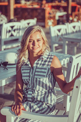 Fototapeta premium Beautiful blond woman relaxing in the sunlight of the sunset on a sunny holiday destination, textured nature outdoors. Healthy living, wellness recreation lifestyle.