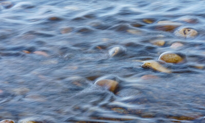 Closeup of Motion-Blurred Water Riffles  Flowing over a Cobble Stone Riverbed